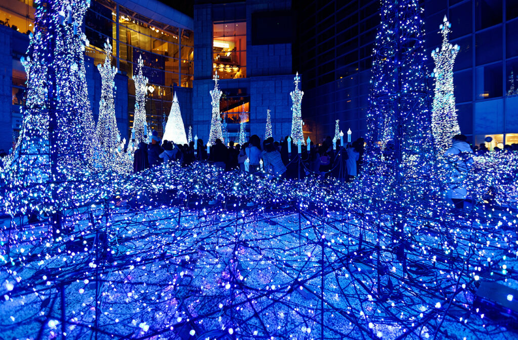 Night scenery of Winter Illumination Display in a pedestrian square in Caretta Shiodome Shopping Area, Tokyo, Japan, with decorated Christmas trees and dazzling lights in a romantic dreamy atmosphere